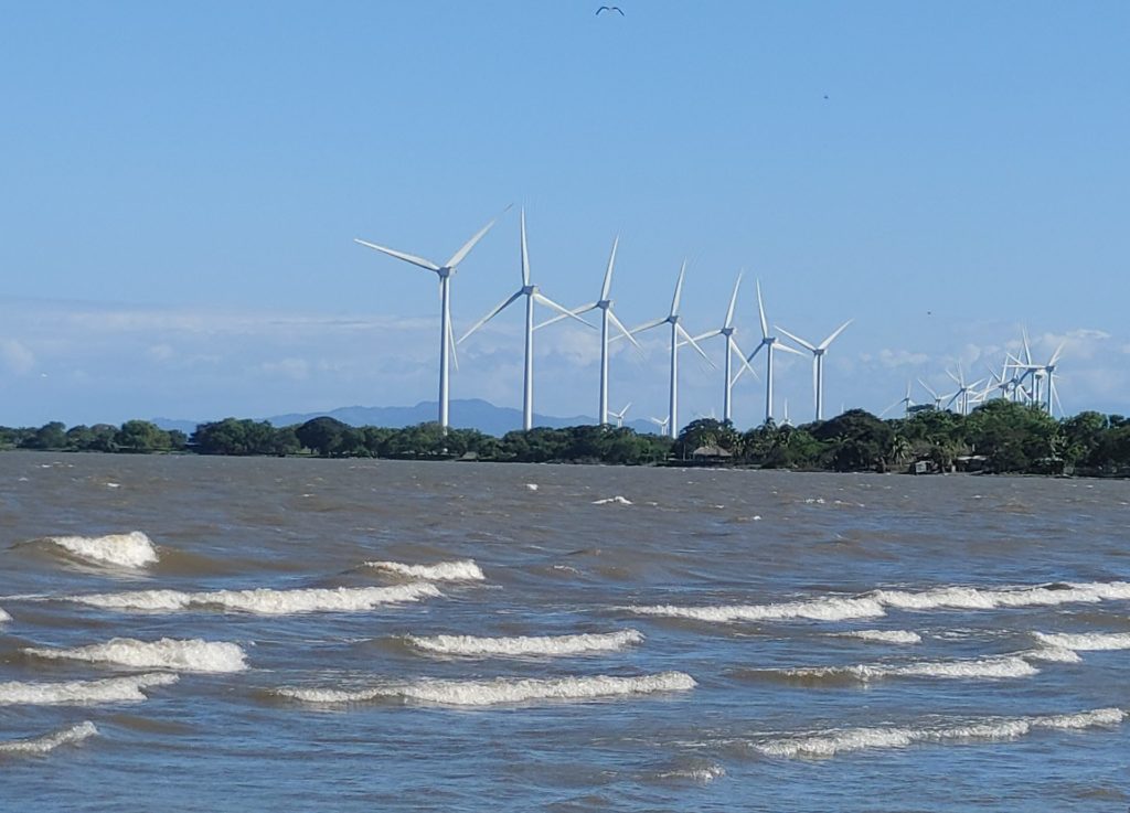 Beach with waves, wind turbines in the distance.